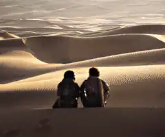 Two people sitting on sand dunes