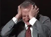 Man in suit laughing and holding head