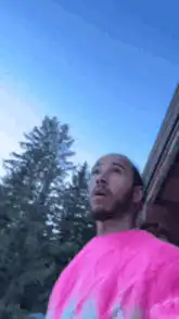 Man in pink shirt pointing at sky