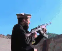 Man in hat firing an assault rifle