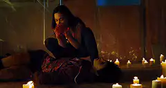 Woman performing CPR on man among candles