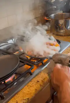 person cooking shrimp in a pan