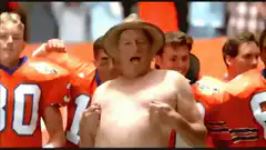 Shirtless man in hat cheering with football players