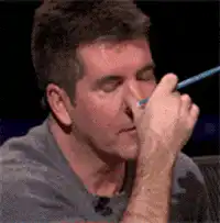 Simon Cowell rubbing his eye with a pen