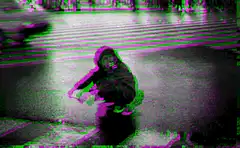 Person squatting on wet street with glitch effects