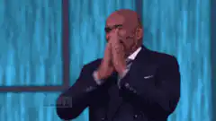 Steve Harvey laughing and covering his face