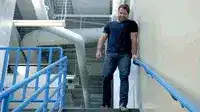 Man walking down stairs with blue railings