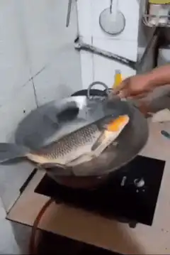 Chef flips large fish in wok