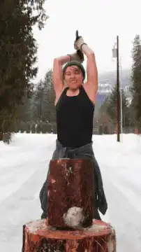 woman splits log in snow