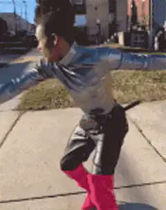 Woman in pink boots doing backflips on sidewalk