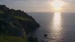 Aerial view of a boat near rocky cliffs at sunset
