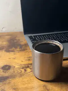 metal cup of black coffee on wooden desk