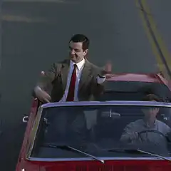 Mr. Bean waving from a convertible