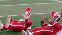 Two cheerleaders sitting on a football field