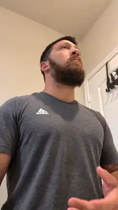 Bearded man in Adidas shirt looking up