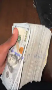 Hand flipping through a thick stack of hundred dollar bills