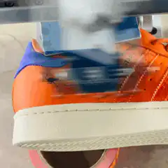 Heat press machine applying logo to orange shoe