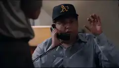 Man in Oakland A's hat on phone