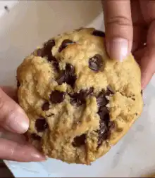 Hands breaking a chocolate chip cookie
