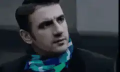 Man in scarf looks around skeptically