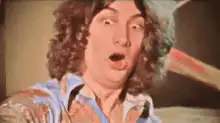 Man with curly hair and mustache making shocked face