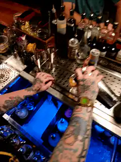 tattooed bartender making a drink