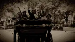 People waving from a carriage in old film