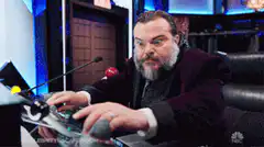 Jack Black playing air guitar on a desk