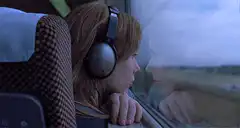 girl with headphones looking out train window