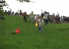 Crowd tumbling down a grassy hill