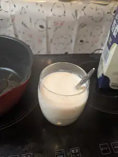 Glass of milk with spoon on stovetop
