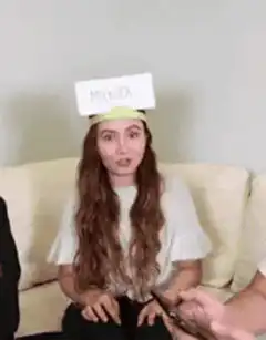 Woman with 'MURDER' card on head