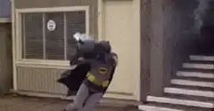 Batman runs with a smoke bomb