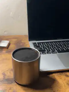 metal cup on desk next to laptop