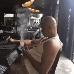 bald man smoking cigar at restaurant