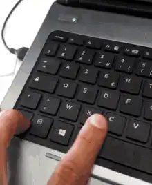 Finger pressing laptop keyboard keys
