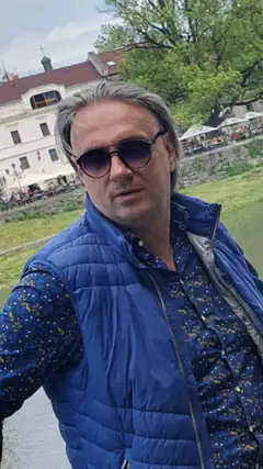 Man in blue vest by river