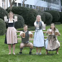 People in dirndl and lederhosen toasting with beer