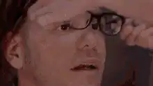 Man lifts glasses and smiles