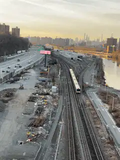 Train moving along tracks near highway and river