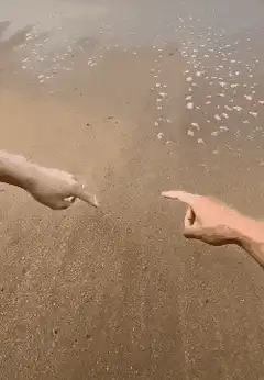 Two hands draw a heart in the sand