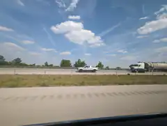View of highway with trucks from moving car