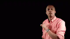 Man in pink shirt pointing and looking at watch