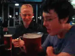 Guy chugs giant beer mug while friend cheers