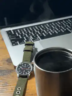 watch next to laptop and coffee