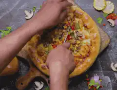 Hands cutting a pizza