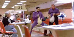 Two men in purple suits juggling bowling balls