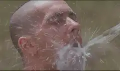 Man spits water on two-headed cat mask