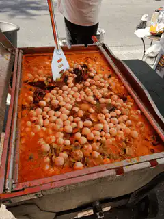 Street vendor cooking snails in a large pan