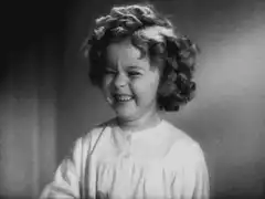 Shirley Temple laughing and covering mouth